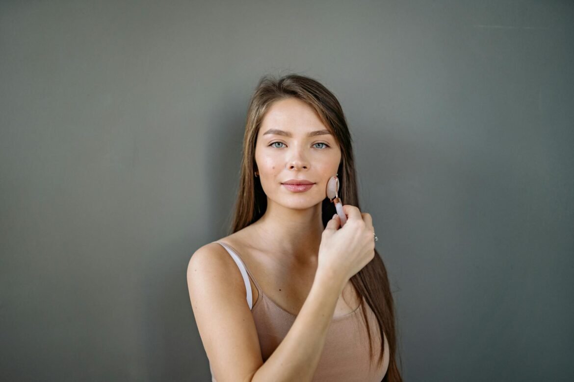 beauty tips for skin - Young woman using jade roller for facial massage and self-care routine.