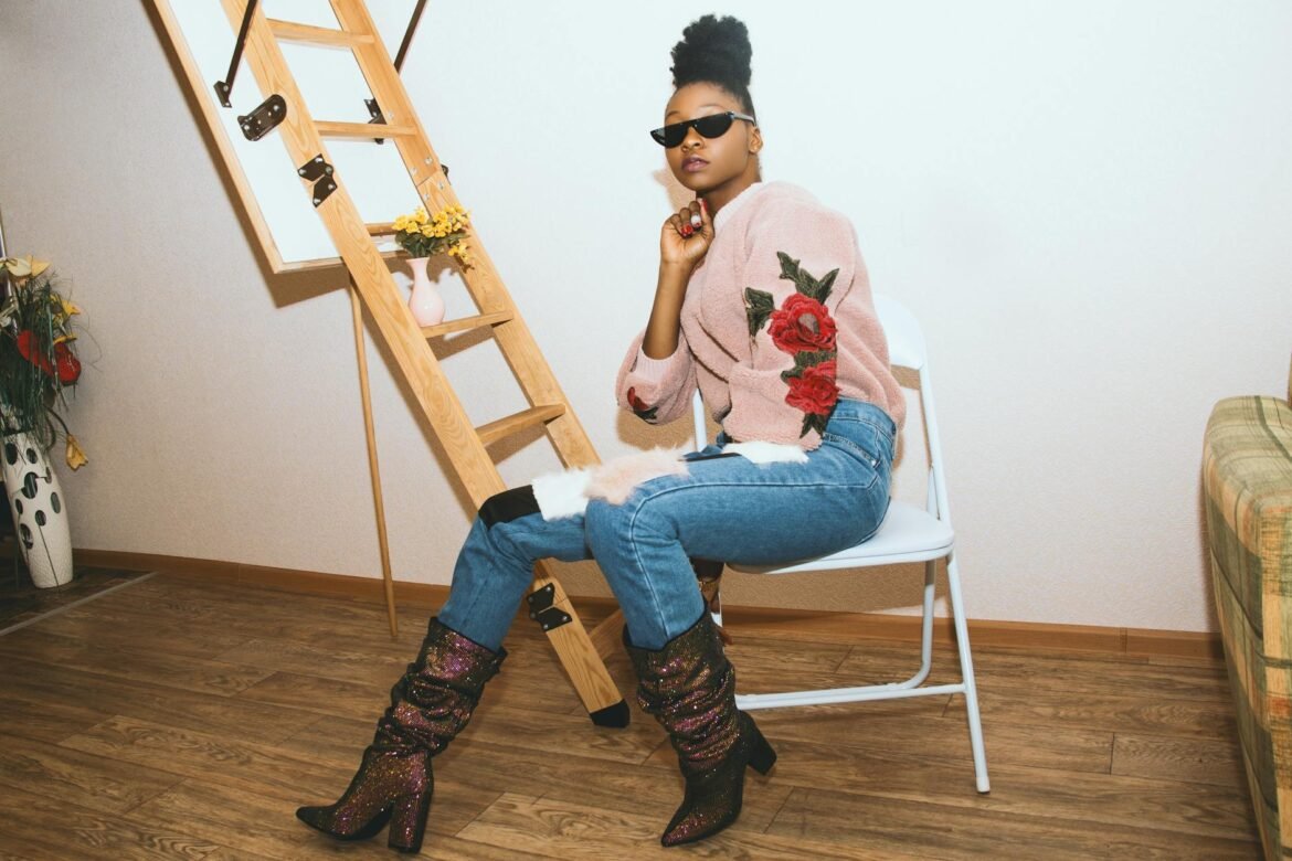 celebrity style inspiration - Elegant woman in a chic outfit posing indoors with sunglasses and stylish boots.